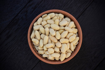 peanuts in ceramic bowl on oak table