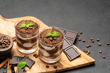 Classic tiramisu dessert in a glass on dark concrete background