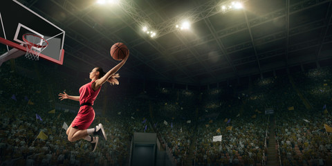 Female basketball player makes slam dunk. Basketball player on big professional arena during the game © Alex