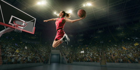 Female basketball player makes slam dunk. Basketball player on big professional arena during the...