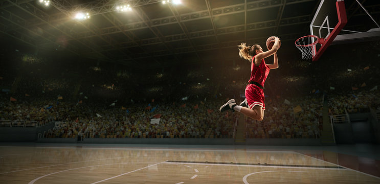 Female basketball player makes slam dunk. Basketball player on big professional arena during the game