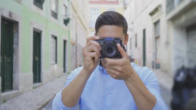 Front view of male photographer with digital camera outdoor. Closeup shot of handsome young man with photo camera. Photography concept