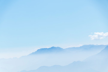Abstract cascade mountain chains silhouette landscape nackground in a light blue mist sky in morning Andes
