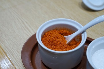 Selective focus of cayenne pepper is seasoning container set for noodle on wooden table in restaurant, Thai food style, Soft focus