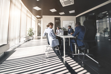 Silhouettes of people sitting at the table. A team of young businessmen working and communicating together in an office. Corporate businessteam and manager in a meeting.