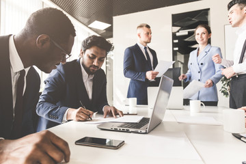 A team of young businessmen working and communicating together in an office. Corporate businessteam and manager in a meeting.