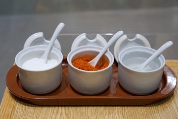 Seasoning container set for noodle to consist of cayenne pepper, sugar and vinegar on wooden table in restaurant, Thai food style, selective focus