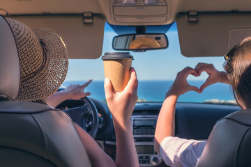 Two girls traveling by car on the Italy. One of them  holds her hands in the form of heart