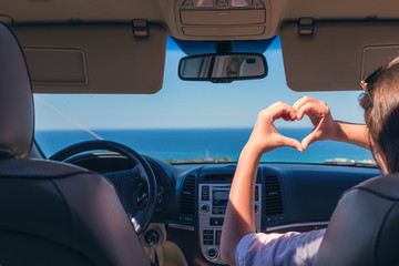 girl traveling by car on the Italy and holds her hands in the form of heart. Travel love symbol.