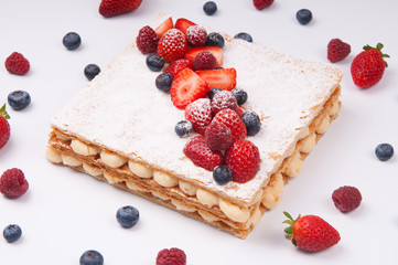 Beautiful puff pastry cake decorated with berries. Close-up of appetizing refreshing dessert with berries around. Bakery shop concept