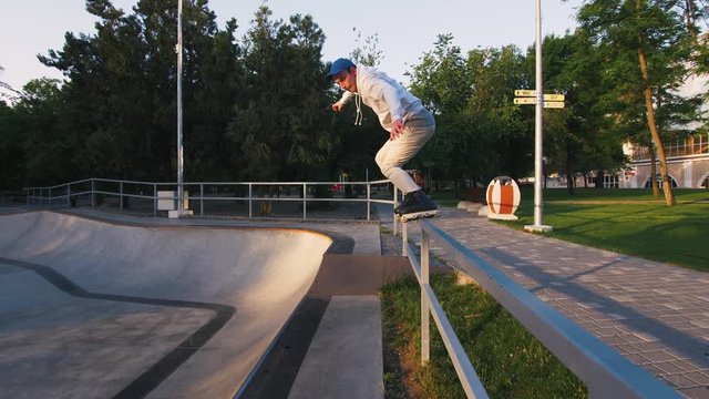 Aggressive Inline roller skater doing tricks in concrete skatepark outdoors, slow motion