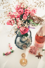 Bouquet of pink roses in a vase and a bottle of champagne on the table