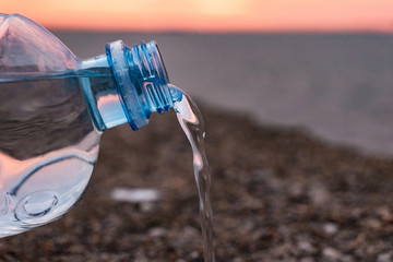 water flows out of a plastic bottle on the sea sand. water saving. last water drop