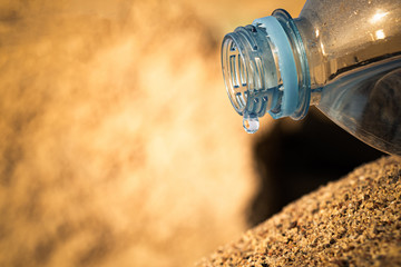 water flows out of a plastic bottle on the sea sand. water saving. last water drop