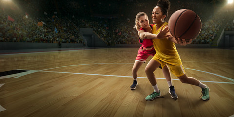 Female basketball players fight for the ball. Basketball players on big professional arena during...