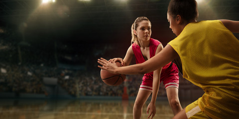 Female basketball players fight for the ball. Basketball players on big professional arena during...