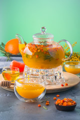 A bright orange teapot on a green background and a stone table