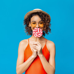 Lovely black girl eating big colorful lollipop