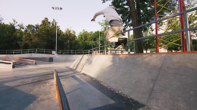 Aggressive Inline roller skater doing tricks in concrete skatepark outdoors, slow motion