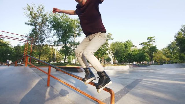 Aggressive Inline roller skater doing tricks in concrete skatepark outdoors, slow motion