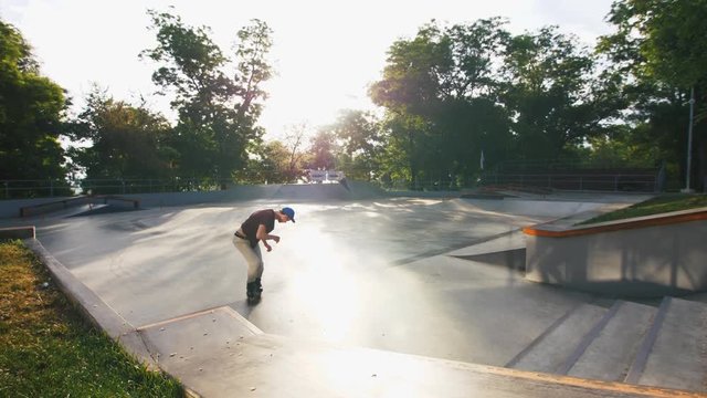 Aggressive Inline roller skater doing tricks in concrete skatepark outdoors, slow motion