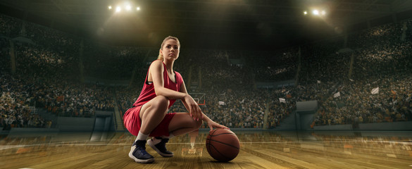 Female basketball player with ball on big professional arena 