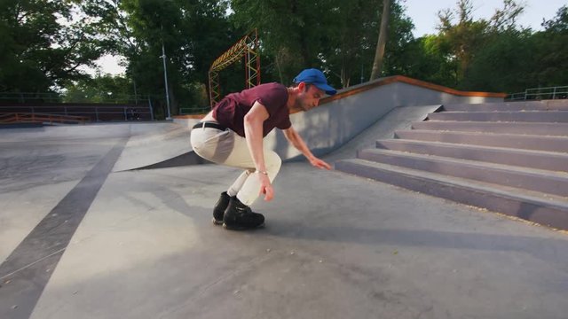 Aggressive Inline roller skater doing tricks in concrete skatepark outdoors, jumping from stairs, slow motion