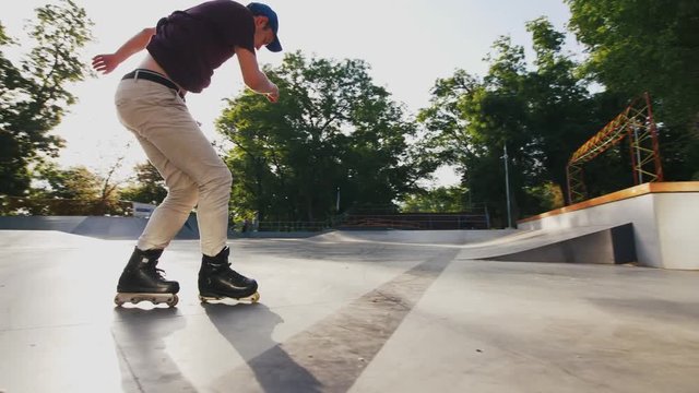 Aggressive Inline roller skater doing tricks in concrete skatepark outdoors, jumping from stairs, slow motion, low angle view