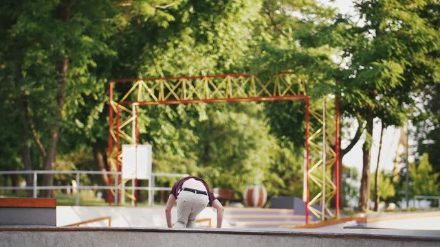 Aggressive Inline roller skater doing tricks in concrete skatepark outdoors with beautiful background, super slow motion
