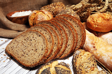 Assortment of baked bread and bread rolls on rustic white bakery table background
