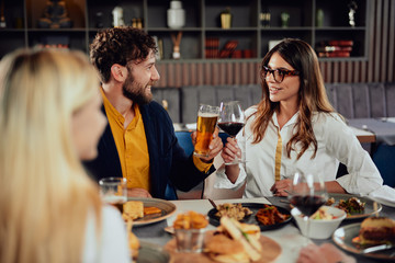 Cheerful Caucasian friends sitting in restaurant and making a toast.