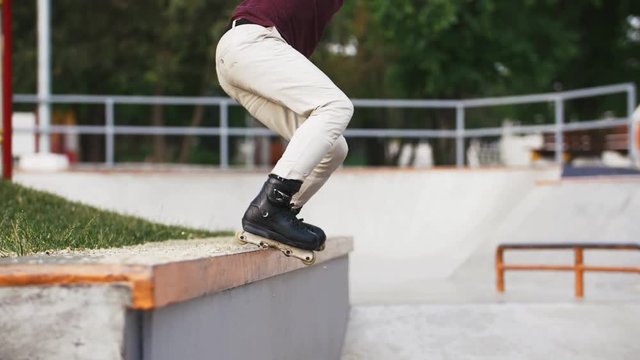 Aggressive Inline roller skater doing tricks in concrete skatepark outdoors with beautiful background, super slow motion