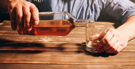 Alcoholic addict. Man pouring from bottle to glass. Dangerous habit. Unhealthy life concept. Social problem.