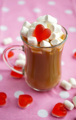 breakfast. transparent small Cup of coffee with milk, decorated with a small marshmallow with a heart of marmalade, on a background of pink tablecloth with white circles