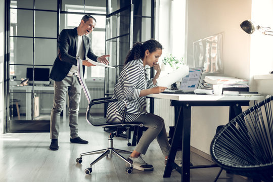 Angry boss shouting at his young trainee for not completing task