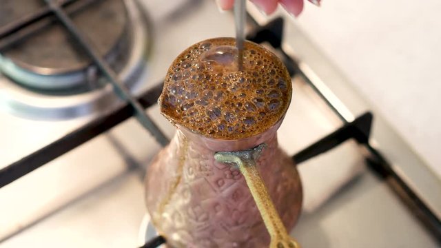 Woman making traditional Bosnian coffee in vintage handmade brass pot at home close up