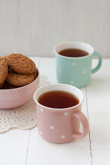 A tasty snack: two cups of tea and a bowl of cookies