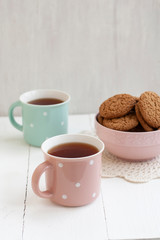 A tasty snack: two cups of tea and a bowl of cookies.