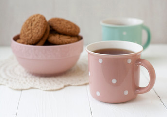 A tasty snack: two cups of tea and a bowl of cookies.