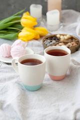 A tasty snack: two cups of tea, a plate of zephyr and a box of sweets.