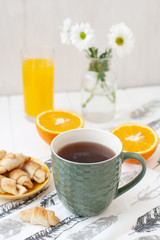 A tasty desert: a cup of tea, a glass of juice, a plate of biscuits.