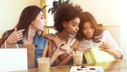 Three female friends sitting in cafe with shopping bags