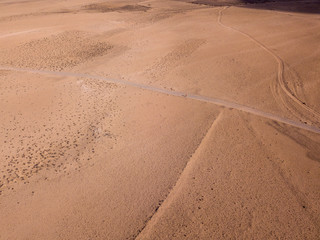 Aerial view of a desert landscape on the island of Lanzarote, Canary Islands, Spain. Road that crosses a desert. A man with a orange t-shirt walking in a desert land