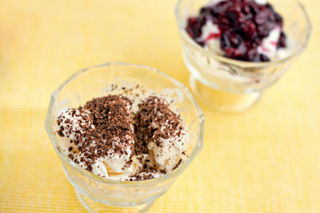 Ice cream dessert with chocolate and currant jam on yellow table-napkin. Selective focus