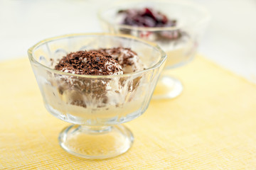 Ice cream dessert with chocolate and currant jam on yellow table-napkin. Selective focus
