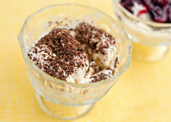 Ice cream dessert with chocolate and currant jam on yellow table-napkin. Selective focus