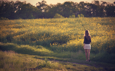 Beautiful woman walking in rapeseed field.
