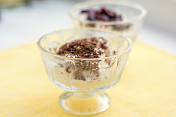 Ice cream dessert with chocolate and currant jam on yellow table-napkin. Selective focus