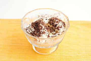 Ice cream dessert with chocolate and currant jam on yellow table-napkin. Selective focus