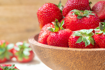 Fresh beautiful strawberries in wooden bowl top view. Strawberry fruits on wooden table copy space.